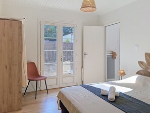 A bedroom with a bed, a chair, a wardrobe, and a door leading to an outdoor area. - Les Cariatides 8 by Interhome (Ile d'Oléron)