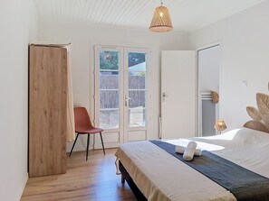 A bedroom with a bed, a chair, a wardrobe, and a door leading to an outdoor area. - Les Cariatides 8 by Interhome (Ile d'Oléron)