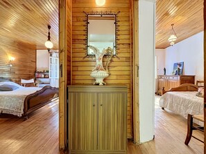 Una habitació amb sostres de fusta, un llit amb llençol blanc, un armari de fusta i un mirall a sobre.