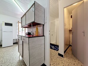 A compact kitchen with a refrigerator, a sink, and a countertop with a bottle and a kettle. - La Bergerie de Portes by Interhome (Portes)