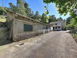 A gravel driveway leading to a building with a sloped roof and a car parked in the background. - La Bergerie de Portes by Interhome (Portes)