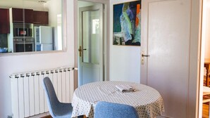 Una habitación con una mesa de comedor, dos sillas, un radiador, una puerta y un cuadro en la pared.