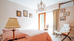 Un dormitorio con cama, una silla, una lámpara y obras de arte en la pared.