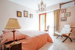 Ein Schlafzimmer mit einem Bett, einem Sessel, einer Lampe und Kunstwerken an der Wand.