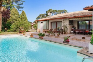 A poolside area with a clear pool, outdoor seating, and potted plants. - La Petite Orée du Bois (SAUGNAC ET CAMBRAN)
