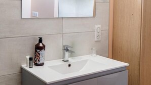 Un baño con un lavamanos blanco, un espejo y un armario de madera.