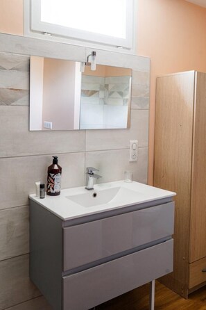 Ein Badezimmer mit Waschbecken, Spiegel und Holzschrank.