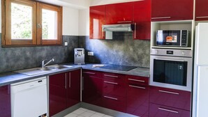 Una cocina con gabinetes rojos, microondas integrado, lavavajillas y dispensador de agua.