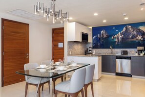 Eine moderne Küche mit Granit Arbeitsplatte, Edelstahlgeräten und einem Essbereich mit Glastisch und Stühlen.