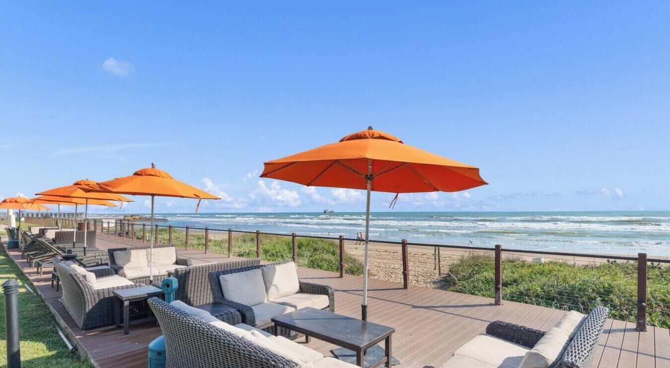 A deck with outdoor seating and umbrellas overlooking the ocean.