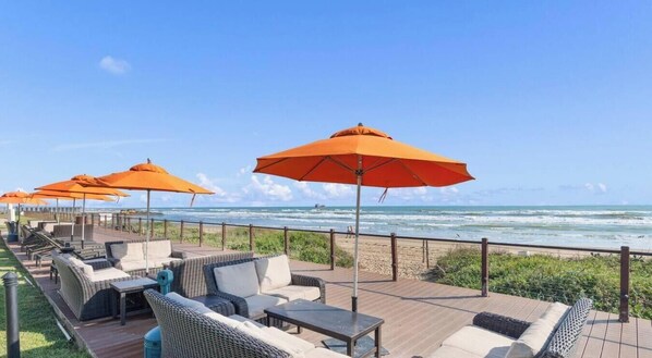 A deck with outdoor seating and umbrellas overlooking the ocean. - 11th Floor Panoramic Views Sunset SpaceX Fireworks (South Padre Island)