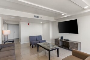 A modern living room with a sofa, a coffee table, and a flat-screen TV mounted on the wall. - 11th Floor Panoramic Views Sunset SpaceX Fireworks (South Padre Island)