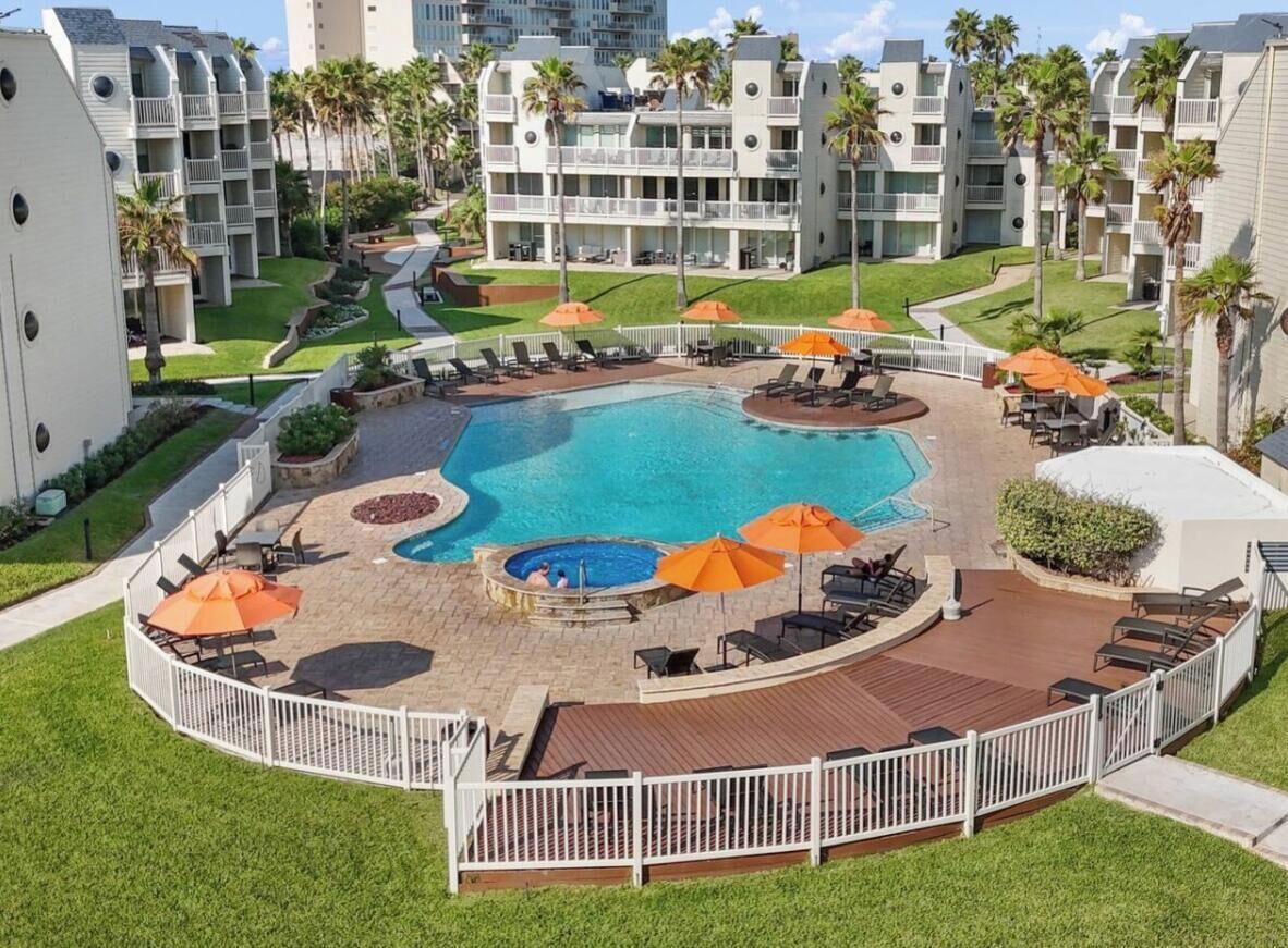 A hotel with a central swimming pool, outdoor seating areas, and a landscaped garden.