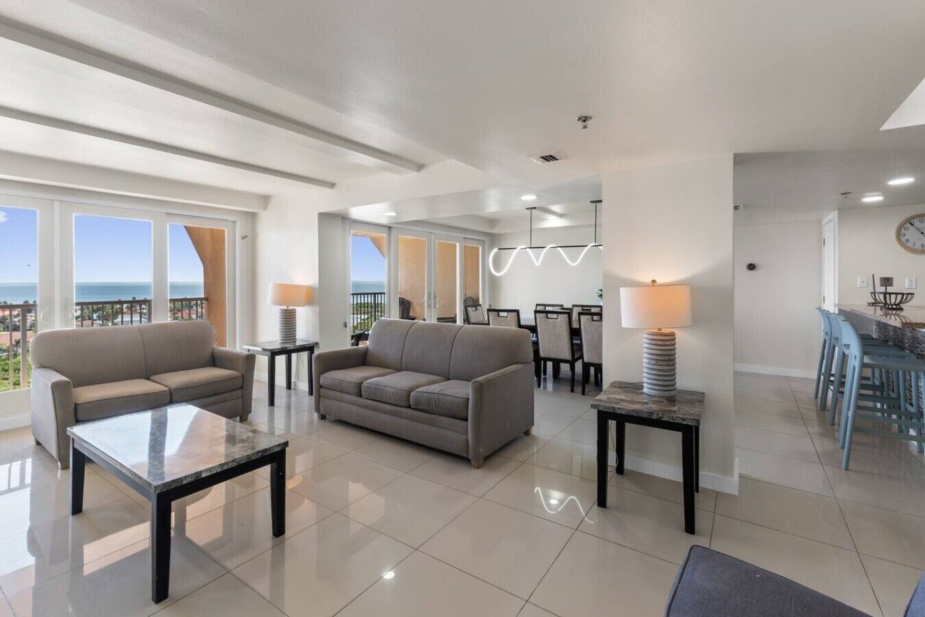 A modern living room with a sofa, coffee table, and dining area with chairs and a table.