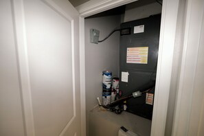 A narrow hallway with a door at the end, a wall-mounted electrical outlet, and a fire extinguisher.