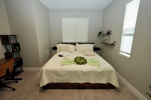 A bedroom with a bed, a desk, and two windows with blinds. - Orlando Escape • Near Disney • 5 Bedrooms (Orlando)