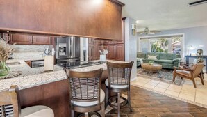 A modern kitchen with dark wood cabinets, stainless steel appliances, and a central island with bar stools. - Pool Oasis - Family Getaway - Hot Tub - Pets OK (Port Orange)