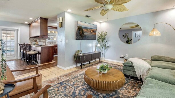 A modern living room with a round coffee table, a sofa, a dining area with chairs, and a kitchen in the background. - Pool Oasis - Family Getaway - Hot Tub - Pets OK (Port Orange)