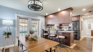 A modern kitchen with a dining area, wooden flooring, and a ceiling fan. - Pool Oasis - Family Getaway - Hot Tub - Pets OK (Port Orange)