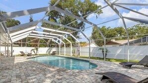 A covered outdoor swimming pool with lounge chairs and a camera on the floor. - Pool Oasis - Family Getaway - Hot Tub - Pets OK (Port Orange)