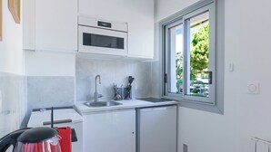 Una cucina compatta con forno a incasso, lavello e finestra vista su zone verdi.