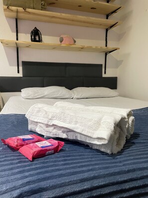 A bed with white linens, a blue striped bedspread, and two pink LifeBelt packages on the bed. - Studio Flamengo on the beachfront block, across from the subway. (Rio de Janeiro)