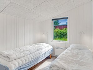Un dormitorio con dos camas, una ventana que da a zonas verdes y un techo blanco.