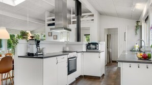 Uma cozinha moderna com armários brancos, forno embutido, micro-ondas e uma ilha grande com pia.