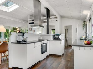 Eine moderne Küche mit weißen Schränken, einem eingebauten Backofen, einer Mikrowelle und einer großen Kochinsel mit Spüle.