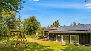 Uma casa com varanda, balanço e área externa coberta.