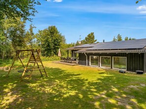 Ein Haus mit Terrasse, Schaukel und überdachter Außenbereich.