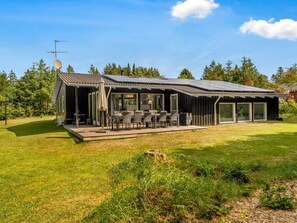 Una casa moderna con terraza, ventanas amplias y antena parabólica.