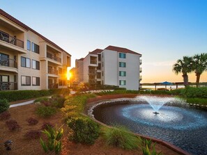 Ein Hotel mit Pool, einem sonnendurchfluteten Innenhof und Blick auf den Sonnenuntergang.