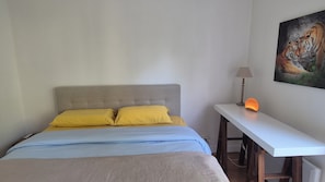 A bedroom with a bed, two pillows, a nightstand with a lamp, and a painting of tigers on the wall. - 2-Room Apartment in Paris and Versailles with Balcony, Terrace, and Greenery (Le Plessis-Robinson)