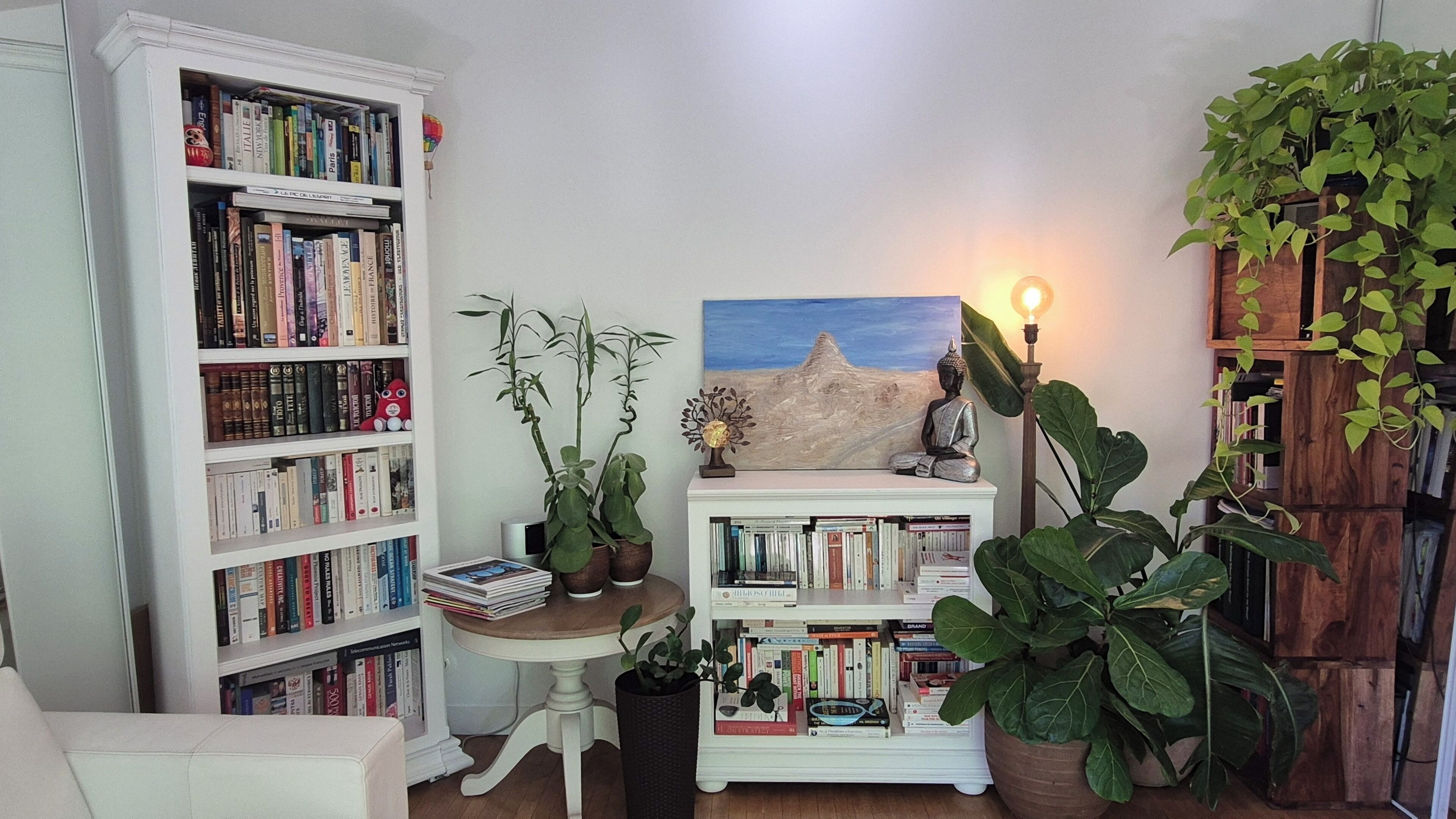 A cozy reading nook with a bookshelf, a small table, and a Buddha statue.