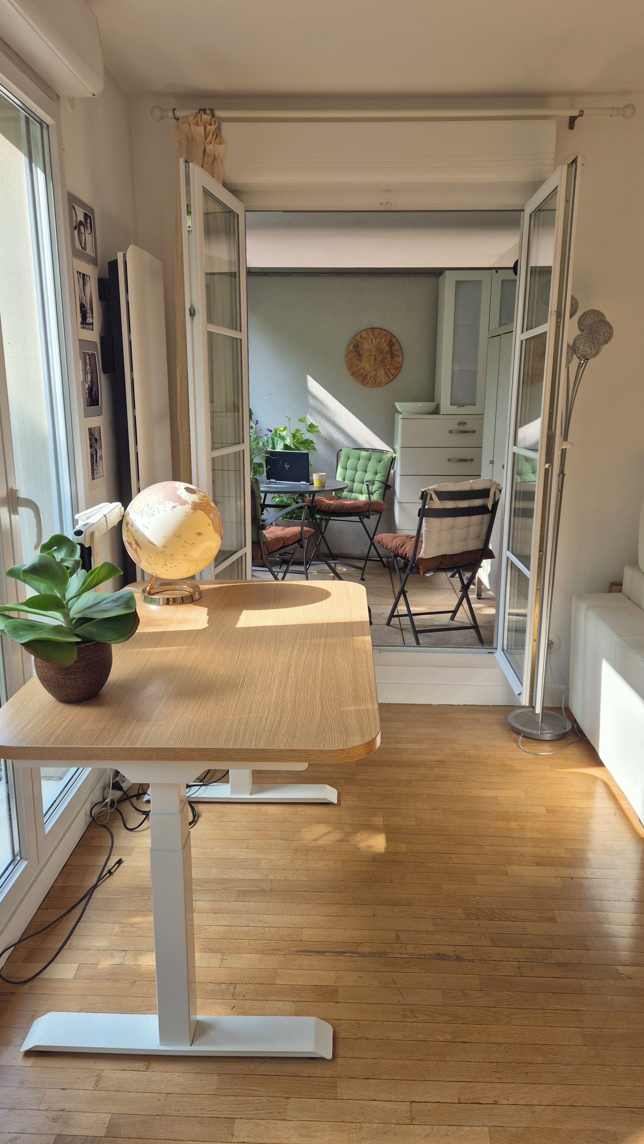 Une chambre moderne avec un plancher en bois, un bureau sur lequel se trouve un globe terrestre, une chaise et une table.