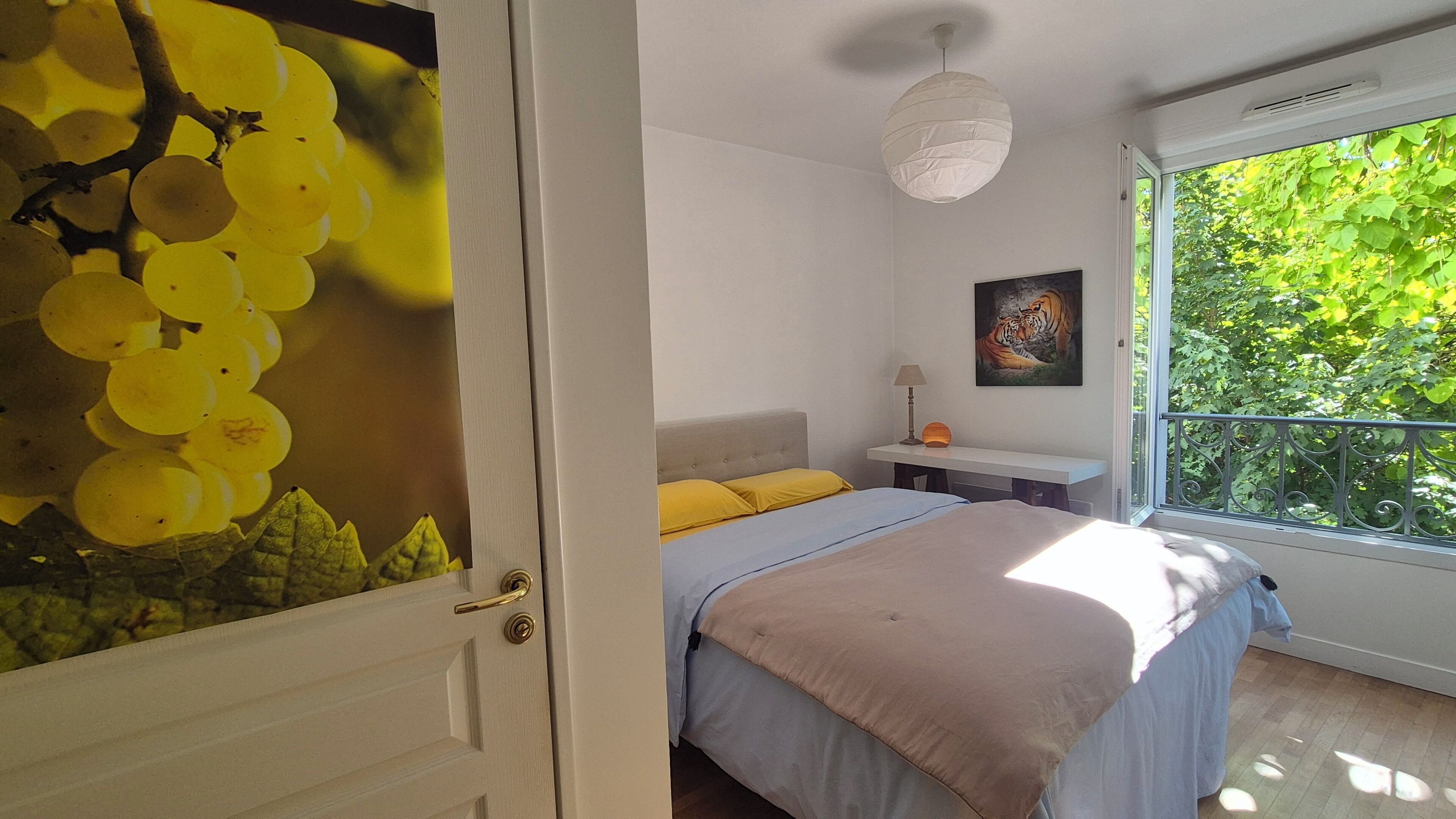 Een slaapkamer met een bed, nachtkastje, lamp en een schilderij van een tijger.