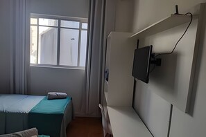 A bedroom with a bed, a window, and a mounted television. - Quarto Triplo Augusta Paulista Frei Cane (São Paulo)