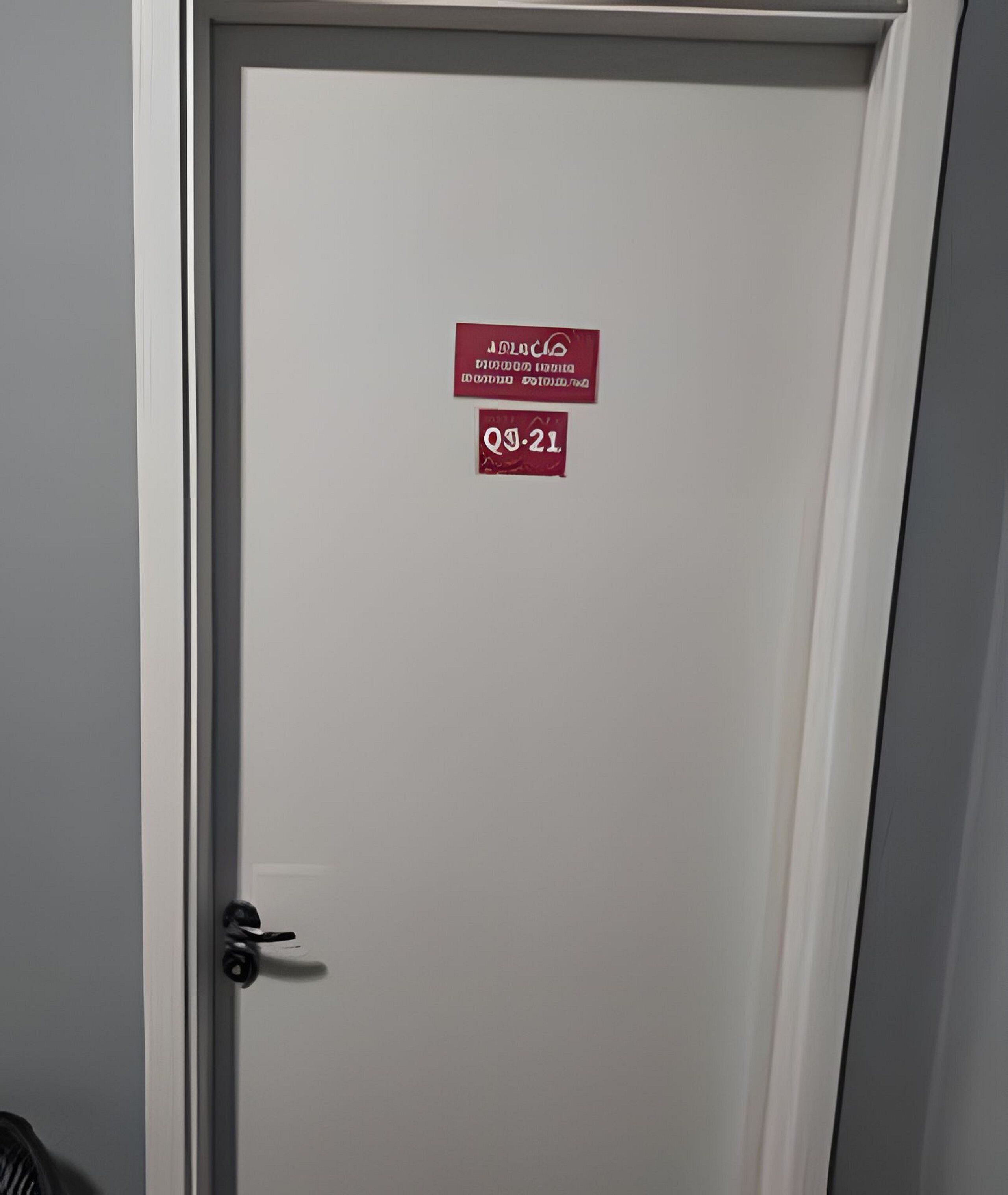 Uma porta fechada com uma placa indicando um número de quarto específico e uma data.