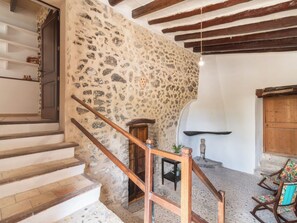 Une pièce avec un mur en pierre, un escalier en bois et des meubles rustiques.