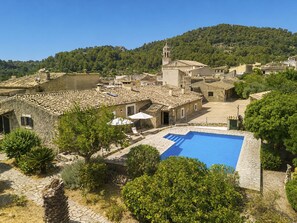 A traditional stone building with a swimming pool, surrounded by greenery and a mountainous backdrop. - Can Toni by Interhome (Mancor de la Vall)