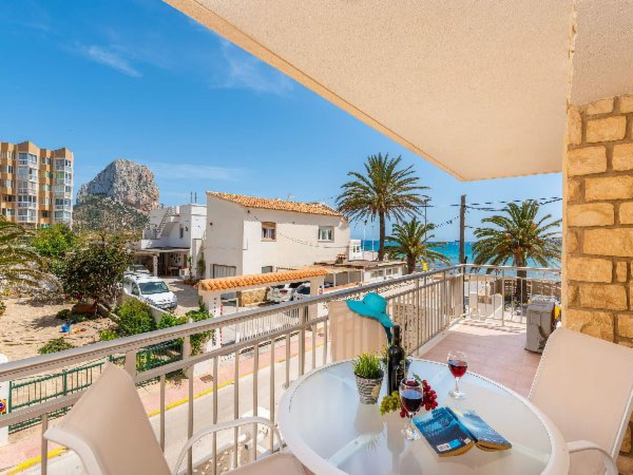 Uma varanda com mesa, cadeiras e vista para o mar e edifícios.