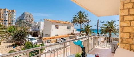 Ein Balkon mit Tisch, Stühlen und Blick auf das Meer und die Gebäude.