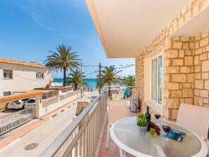Un balcone con un tavolo, una pianta in vaso e una bottiglia di vino.