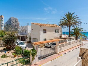 Un edificio costiero con tetto in tegole, un ripostiglio auto e vista sul mare.