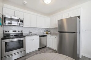 A modern kitchen with white cabinets, stainless steel appliances, a built-in oven, and a refrigerator. - Estero Beach & Tennis - Where Every Stay Comes with a WATERFRONT VIEW 405C (Fort Myers Beach)
