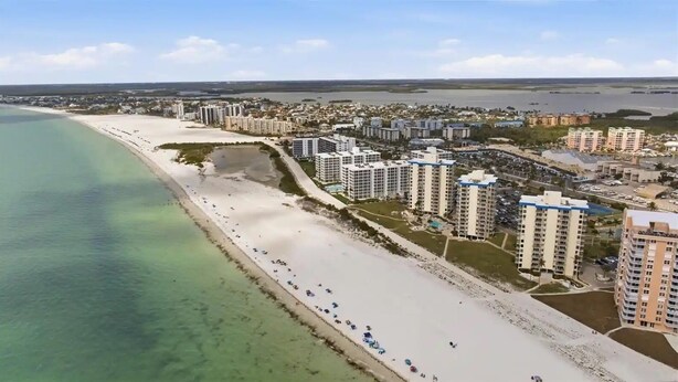 Eine Küstenwohngegend mit Strandhäusern, klarem Wasser und einer Mischung aus Hoch- und Tiefbau.