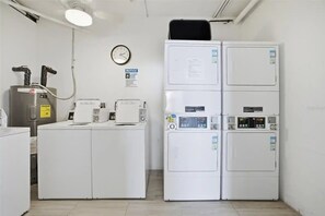 A laundry room with stacked washers and dryers, a clock, and a notice sign. - Estero Beach & Tennis - Where Every Stay Comes with a WATERFRONT VIEW 405C (Fort Myers Beach)