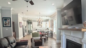 Un salon moderne avec un canapé en cuir, une table basse, une cheminée et un téléviseur.
