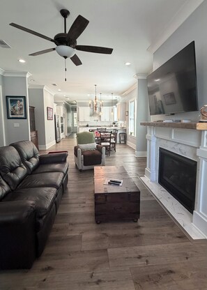A modern living room with a leather sofa, a coffee table, a fireplace, and a TV. - Beautiful 2-bedroom, newly built home situated in historic Old Town Bay St Louis (Bay St. Louis)